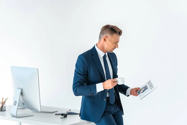 Schöner Geschäftsmann mit Tasse Kaffee und Zeitungslektüre isoliert auf weiß — Stockfoto