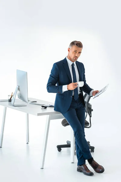 Bel homme d'affaires tenant tasse de café et journal isolé sur blanc, regardant la caméra — Photo de stock