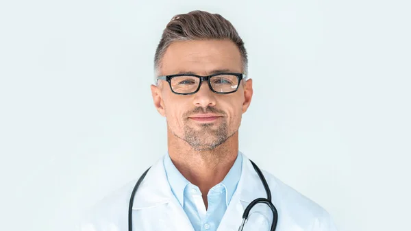 Cheerful handsome doctor in glasses with stethoscope on shoulders looking at camera isolated on white — Stock Photo