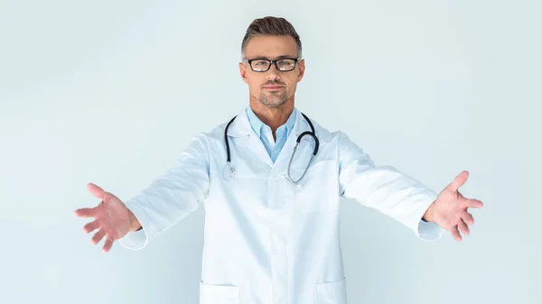 Guapo doctor en gafas con estetoscopio sobre hombros de pie con los brazos abiertos aislados en blanco - foto de stock