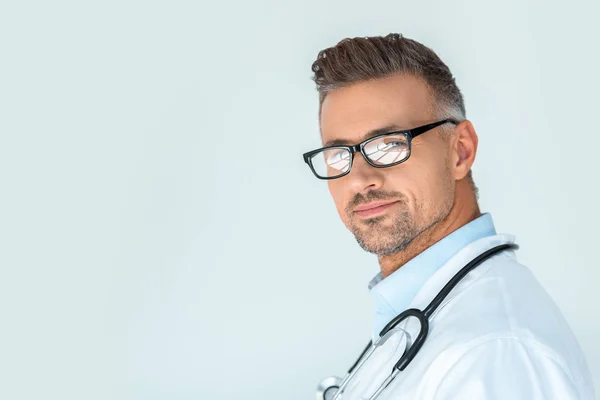 Retrato de médico guapo en gafas con estetoscopio en hombros mirando a la cámara aislada en blanco - foto de stock