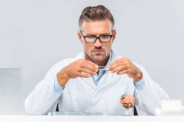 Handsome scientist in glasses looking at reagent isolated on white — Stock Photo