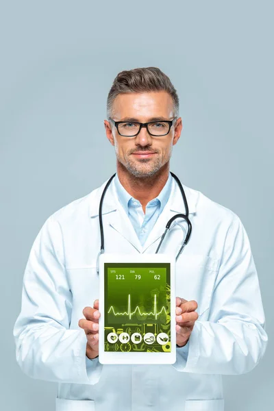 Красивий лікар зі стетоскопом, що показує планшет з медичним приладом ізольовано на білому — стокове фото
