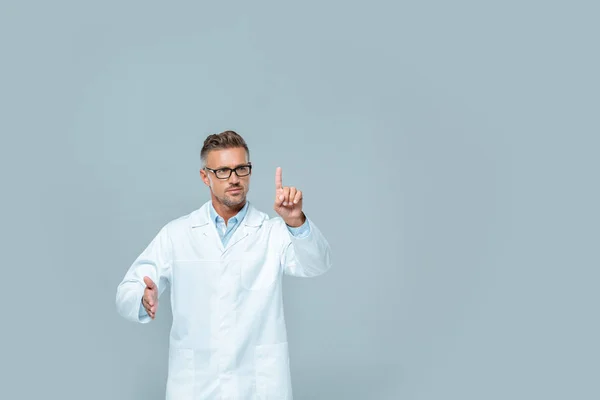 Cientista bonito em óculos tocando algo no ar isolado em cinza, conceito de inteligência artificial — Fotografia de Stock
