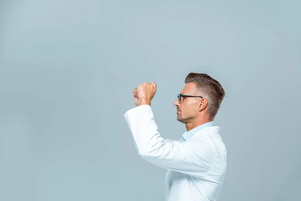 Seitenansicht eines gut aussehenden Wissenschaftlers mit Brille, der etwas Isoliertes auf grauem, künstlichem Intelligenzkonzept berührt — Stockfoto