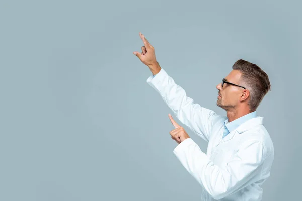 Side view of handsome scientist in glasses moving something isolated on grey, artificial intelligence concept — Stock Photo