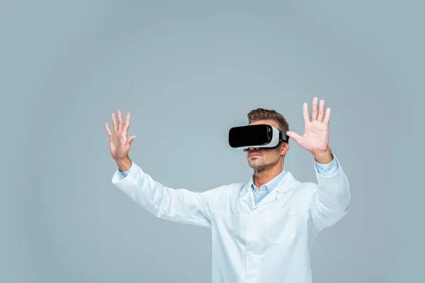 Учёный в наушниках виртуальной реальности трогает что-то в воздухе, изолированное от серого, искусственного интеллекта — стоковое фото