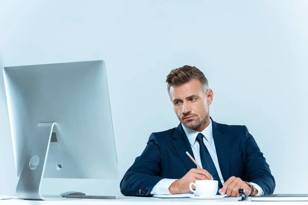 Bell'uomo d'affari che guarda il computer a tavola isolato su bianco — Foto stock