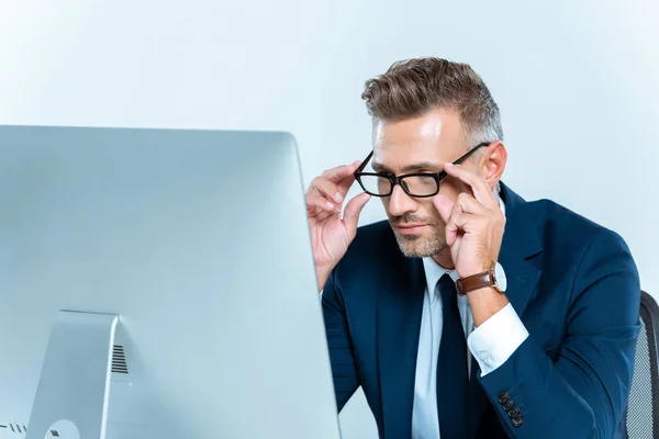 Портрет красивого бізнесмена в окулярах і дивиться на комп'ютер за столом ізольовано на білому — стокове фото