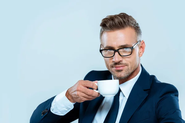 Bell'uomo d'affari che beve caffè e guarda la telecamera isolata sul bianco — Foto stock