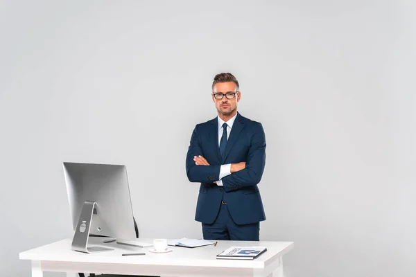 Handsome businessman standing with crossed arms and looking at camera isolated on white — Stock Photo