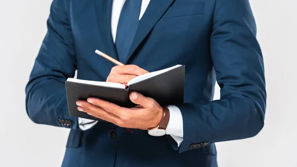 Cropped image of businessman writing something in notebook with pencil isolated on white — Stock Photo