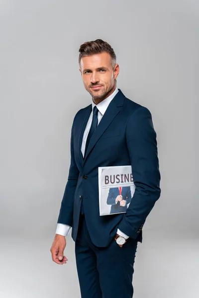 Handsome cheerful businessman holding newspaper and looking away isolated on white — Stock Photo