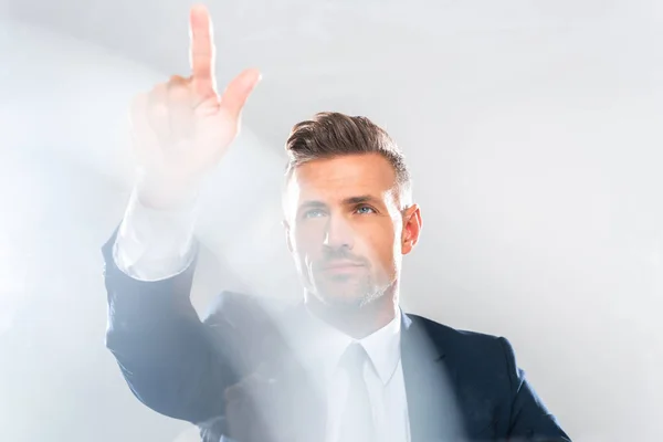 Hombre de negocios guapo en traje tocando algo aislado en blanco, concepto de inteligencia artificial - foto de stock