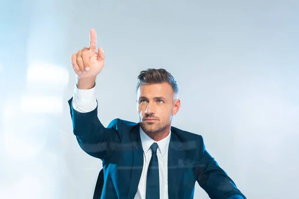 Homem de negócios bonito apontando em algo isolado em branco, conceito de inteligência artificial — Fotografia de Stock