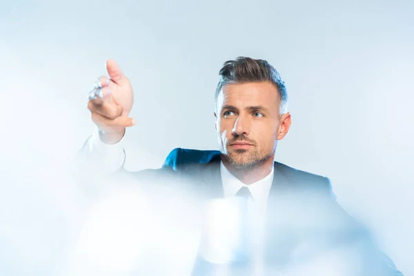 Bonito adulto empresário no terno tocando algo isolado no branco, conceito de inteligência artificial — Fotografia de Stock