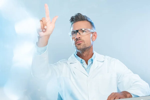 Cientista bonito em óculos de proteção tocando algo isolado em branco, conceito de inteligência artificial — Fotografia de Stock