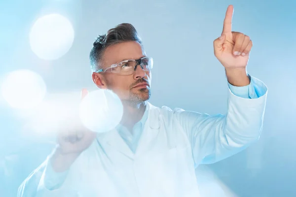 Bonito tecnólogo em óculos de proteção e casaco branco tocando algo isolado em branco, conceito de inteligência artificial — Fotografia de Stock