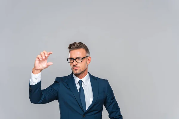 Gutaussehender Geschäftsmann mit Brille, der etwas Isoliertes auf grauem, künstlichem Intelligenzkonzept hält — Stockfoto