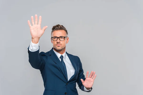 Schöner Geschäftsmann in blauem Anzug und Brille, der etwas Isoliertes auf grauem, künstlichem Intelligenzkonzept berührt — Stockfoto