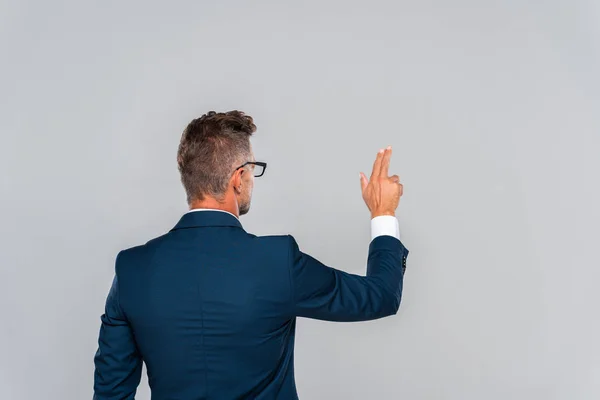 Vue arrière de l'homme d'affaires en lunettes touchant quelque chose d'isolé sur gris, concept d'intelligence artificielle — Photo de stock