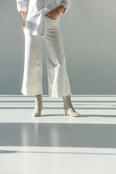 Image recadrée de la femme en pantalon et chaussures à la mode debout sur blanc — Photo de stock