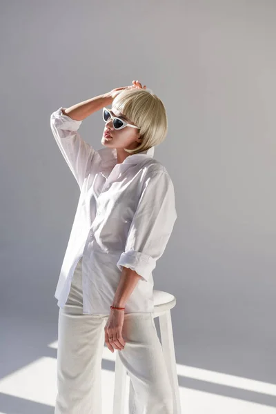 Attractive blonde woman in sunglasses and fashionable white outfit on white — Stock Photo