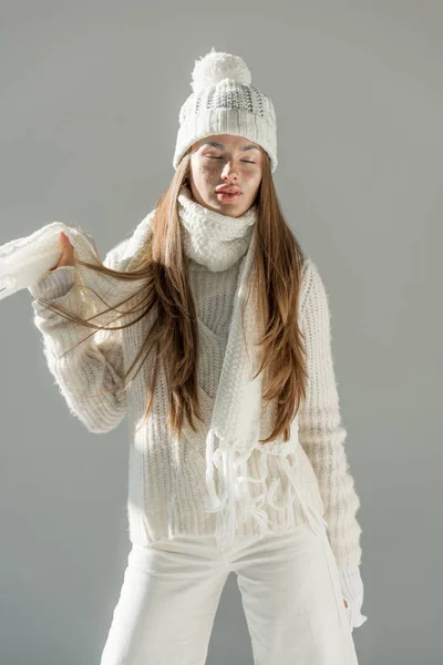 Attraktive Frau in modischem Winterpullover und Schal, die mit geschlossenen Augen auf weißem Hintergrund steht — Stockfoto