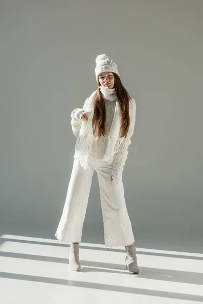 Attractive woman in fashionable winter sweater and scarf standing on white — Stock Photo