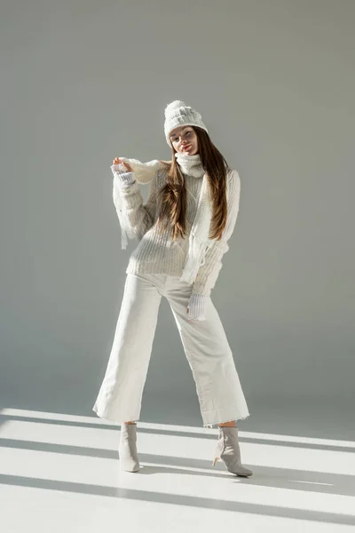Привлекательная женщина в модном зимнем свитере и шарфе позирует на белом — стоковое фото