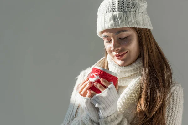 Mulher atraente em camisola de inverno elegante e cachecol segurando xícara de chá isolado em cinza — Fotografia de Stock
