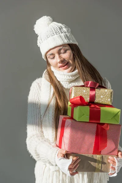 Attractive woman in fashionable winter sweater and scarf holding presents isolated on grey — Stock Photo