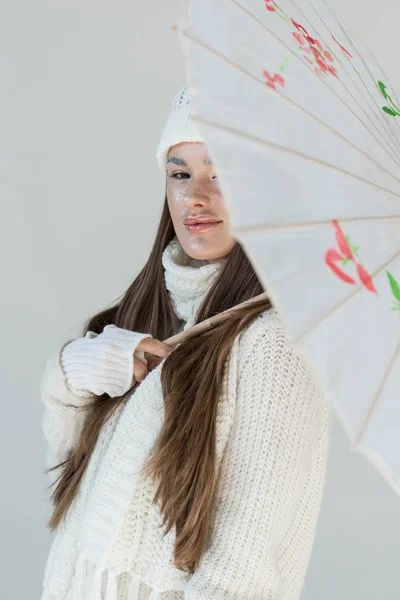 Porträt einer attraktiven Frau in modischem Winterpullover und Schal mit japanischem Regenschirm auf weißem Hintergrund — Stockfoto