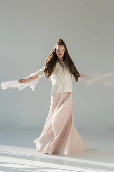 Attractive woman in fashionable winter sweater and skirt spinning around on white — Stock Photo