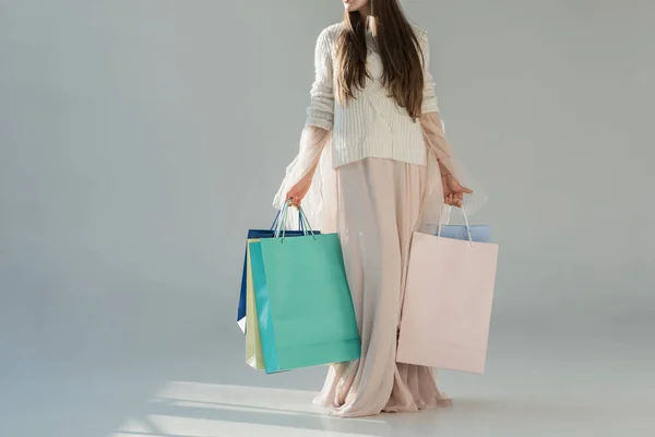 Image recadrée de la femme en tenue d'hiver à la mode debout avec des sacs à provisions sur blanc — Photo de stock