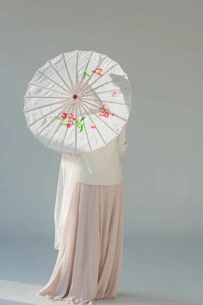 Visão traseira da mulher atraente na roupa de inverno elegante em pé com guarda-chuva japonês no branco — Fotografia de Stock