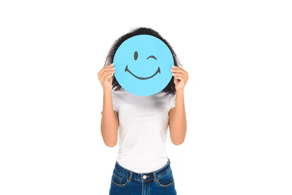 African american girl holding round, blue sign with winking face expression isolated on white — Stock Photo