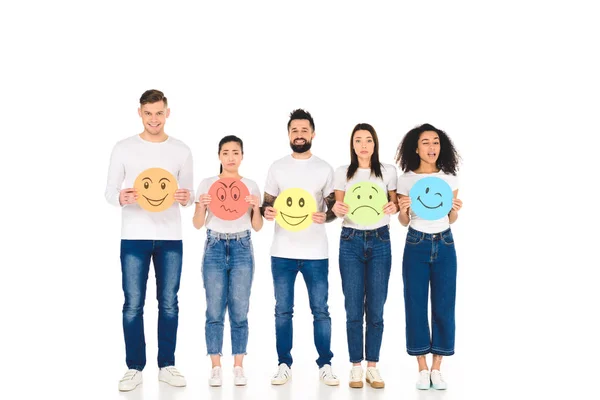 Amigos multiculturales sosteniendo diferentes signos multicolores con expresiones faciales aisladas en blanco - foto de stock