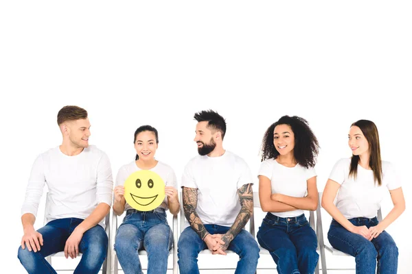 Multicultural friends in white t-shirts looking at girl with happy sign isolated on white — Stock Photo