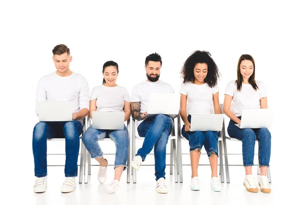 Grupo alegre multicultural de jovens usando laptops isolados em branco — Fotografia de Stock