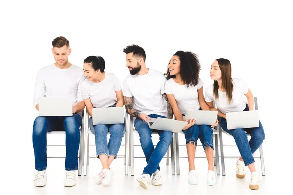 Multicultural curioso grupo de jóvenes mirando portátil aislado en blanco - foto de stock