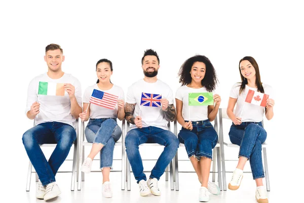 Gruppo multiculturale di persone sedute su sedie con bandiere di diversi paesi isolati su bianco — Foto stock