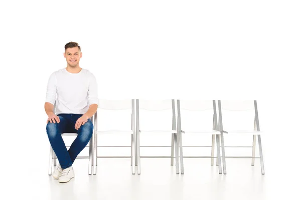 Cheerful smiling man sitting alone isolated on white — Stock Photo