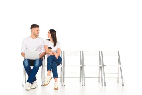 Menina atraente sentado com café para ir e flertando com homem bonito isolado no branco — Fotografia de Stock