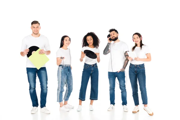 Multikulturelle Gruppe junger Menschen, die mit Kopfhörern Musik hören und Schallplatten isoliert auf weiß halten — Stockfoto