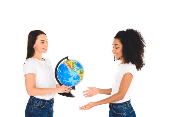 Улыбающаяся женщина, держащая глобус рядом с африканской американской девушкой, изолированной на белом — стоковое фото