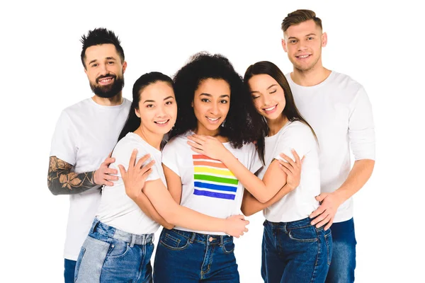 Grupo multiétnico de jóvenes sonriendo y abrazándose con mujer afroamericana con letrero lgbt en camiseta aislada en blanco - foto de stock