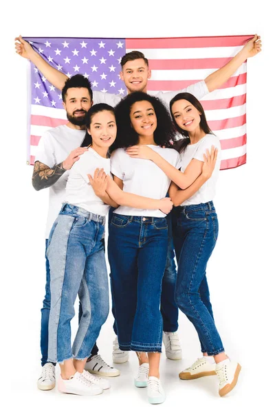 Groupe multiculturel de jeunes gens souriant et étreignant tout en tenant drapeau des Etats-Unis isolé sur blanc — Photo de stock