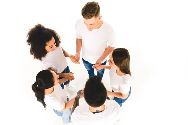 Overhead view of multiethnic group of young people holding hands and standing in circle isolated on white — Stock Photo