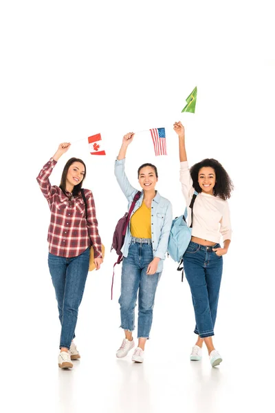 Веселі дівчата з прапорами різних країн над головами ізольовані на білому — стокове фото